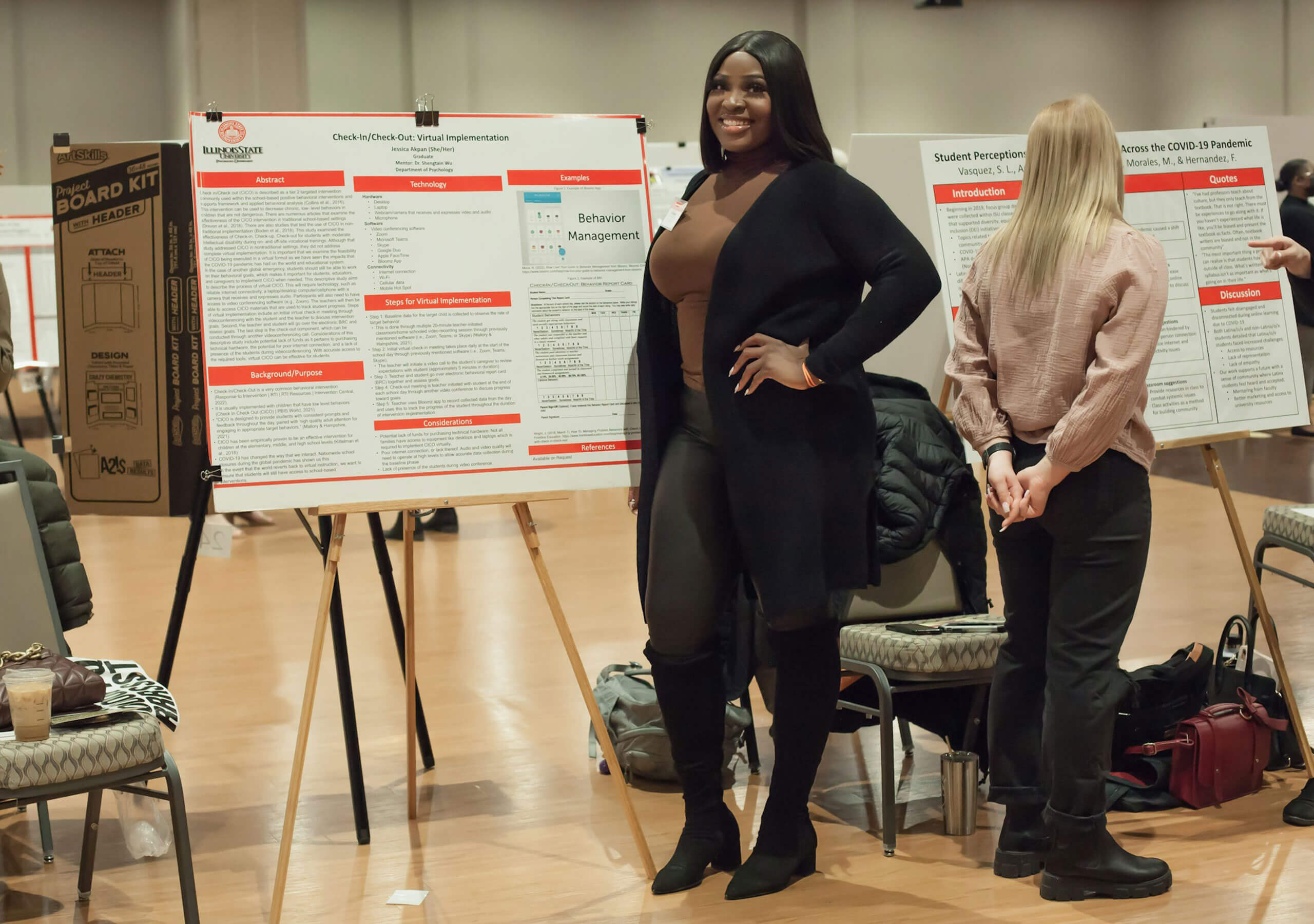 A student pointing to their research poster while explaining their work.